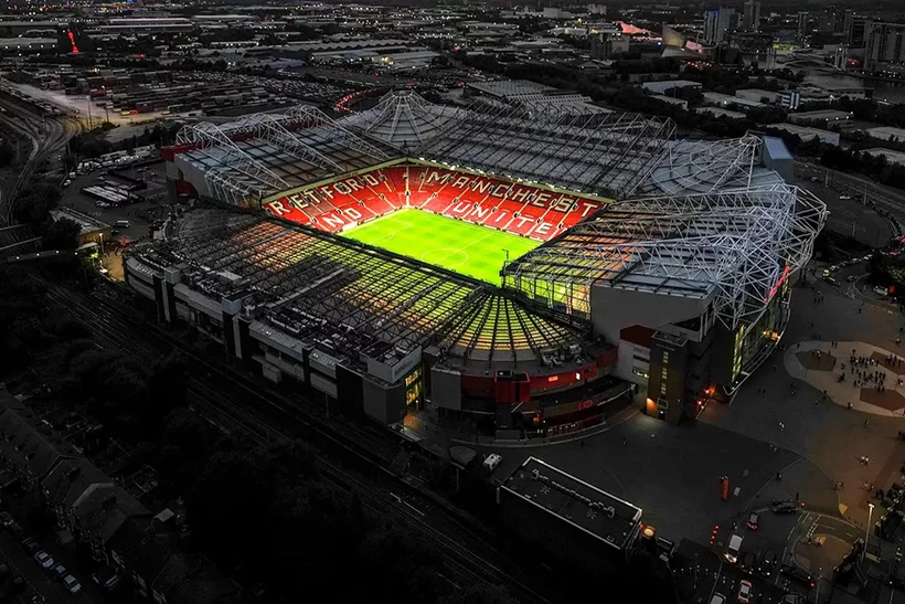 Ảnh bìa Manchester United sân Old Trafford dưới ánh đèn.