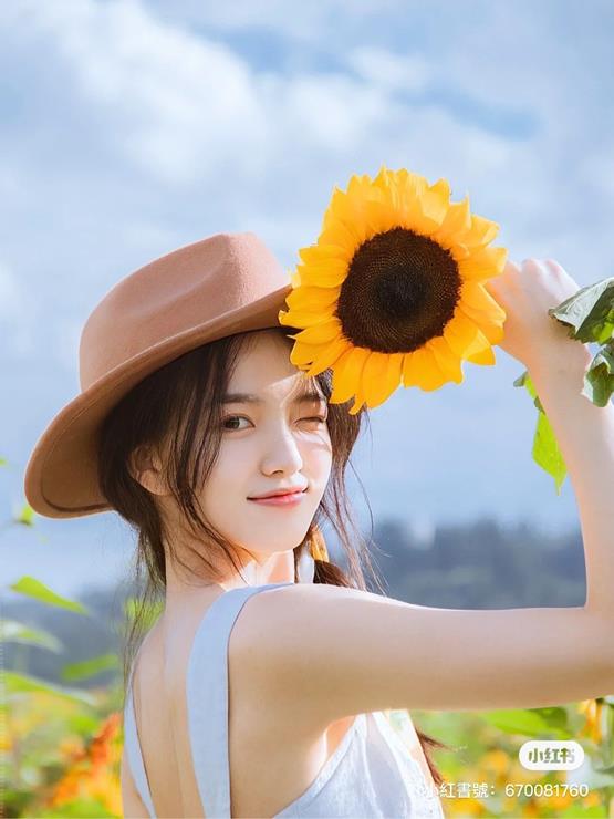 cô gái cầm hoa hướng dương dưới nắng vàng