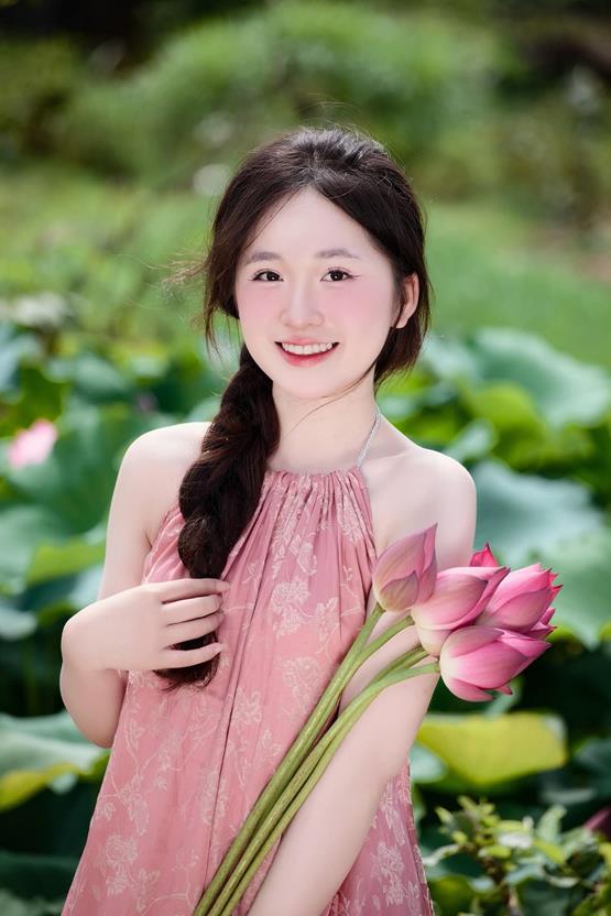 cô gái cầm hoa sen hồng cười tươi