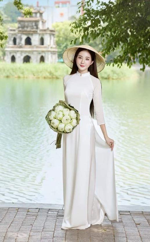 gái xinh cầm hoa sen trắng bên bờ hồ