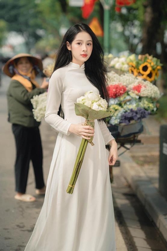 gái xinh cầm hoa sen trắng trên phố