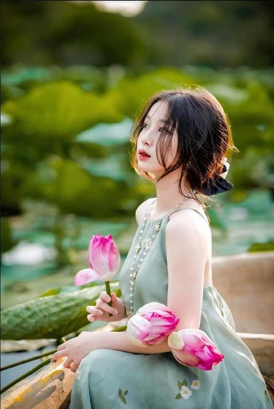 cô gái cầm hoa sen hồng suy tư
