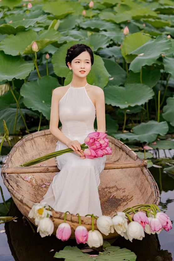 cô gái cầm hoa sen hồng ngồi trên thuyền