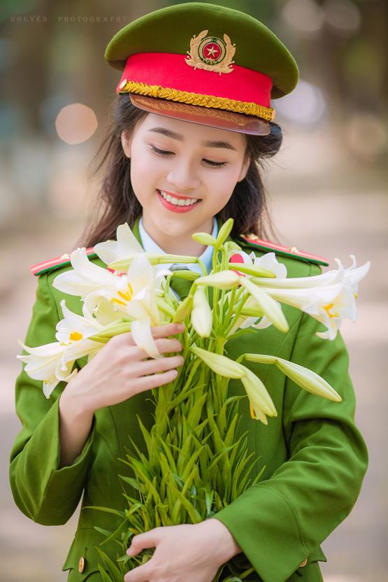 Hình nữ công an xinh đẹp cùng hoa loa kèn